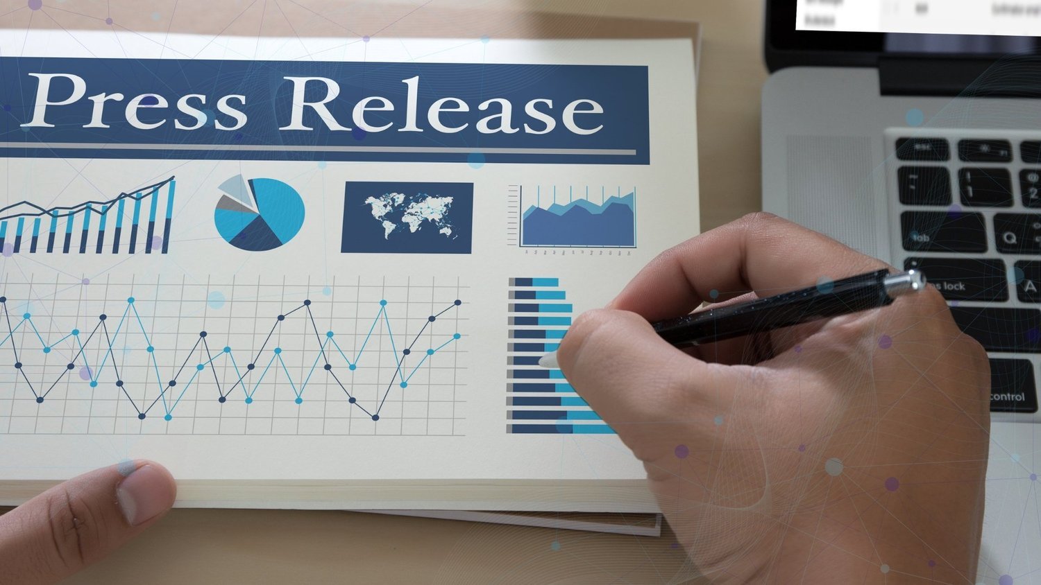 Person reviewing a press release report with charts beside a laptop and digital network graphics.